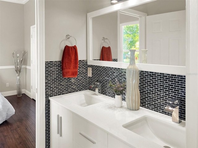 bathroom with decorative backsplash, wood finished floors, double vanity, and baseboards