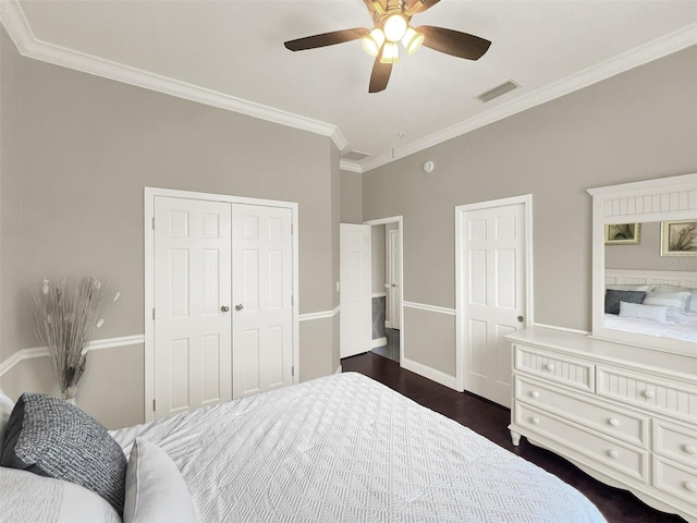 bedroom with crown molding, ceiling fan, a closet, dark wood-type flooring, and baseboards