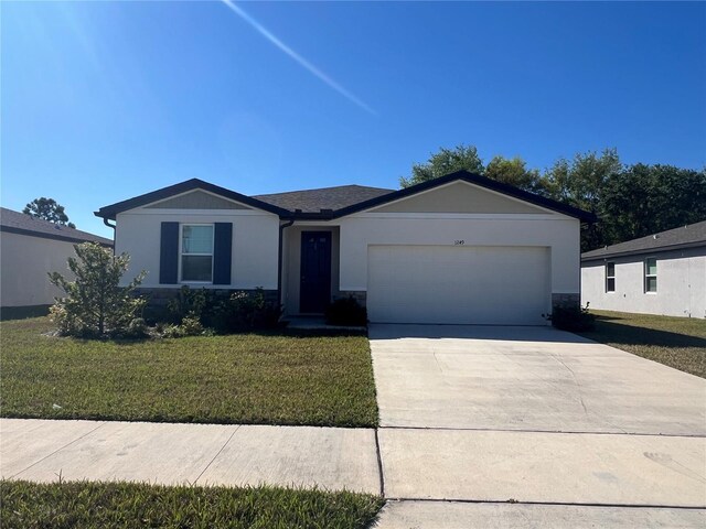 ranch-style house with concrete driveway, an attached garage, stone siding, and a front yard