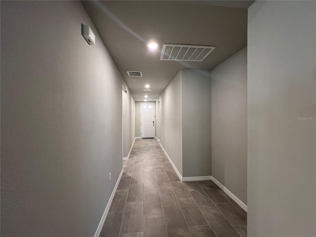 hallway with baseboards, visible vents, and wood finish floors