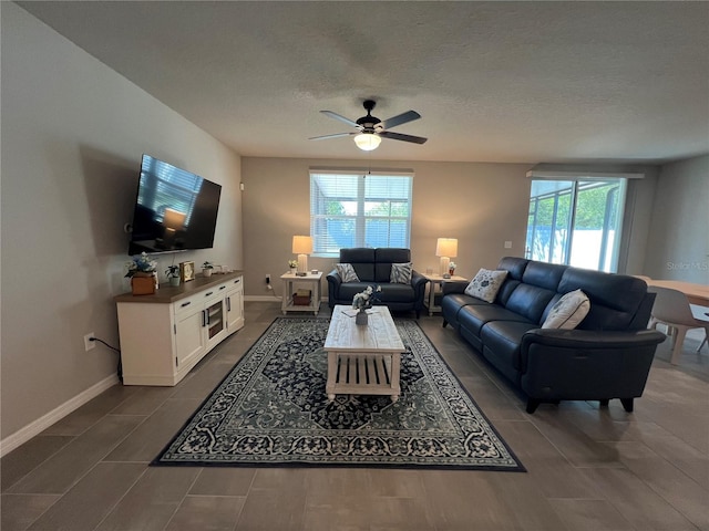 living room with a textured ceiling, baseboards, and ceiling fan