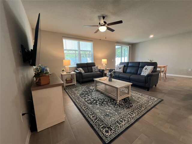 living area featuring baseboards, a textured ceiling, and ceiling fan