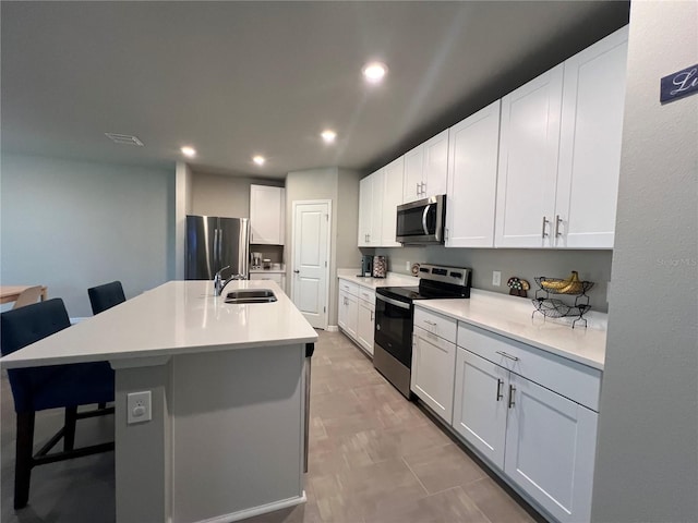 kitchen featuring recessed lighting, a sink, light countertops, appliances with stainless steel finishes, and a kitchen breakfast bar