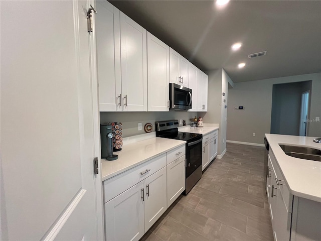 kitchen featuring visible vents, a sink, stainless steel appliances, light countertops, and white cabinets