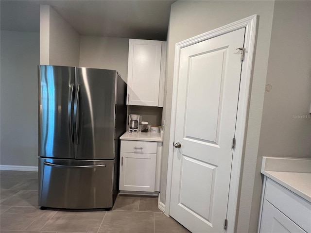 kitchen featuring white cabinetry, light countertops, light tile patterned flooring, and freestanding refrigerator