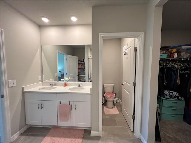 full bathroom featuring a sink, toilet, double vanity, and a spacious closet
