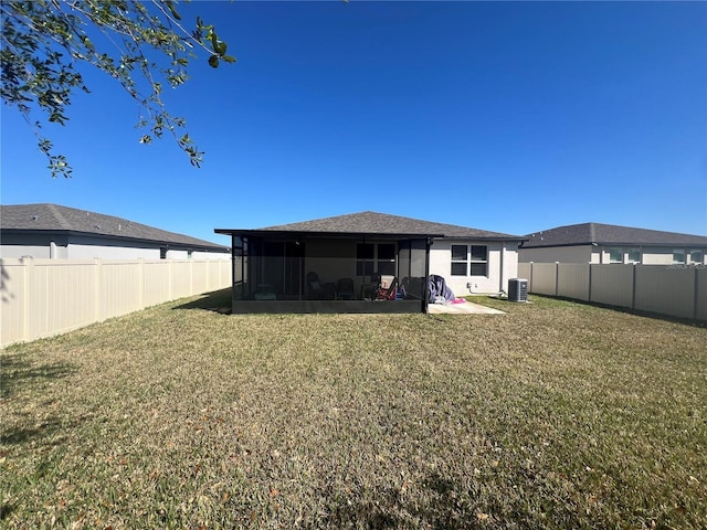 rear view of house featuring a sunroom, stucco siding, central AC unit, a fenced backyard, and a yard
