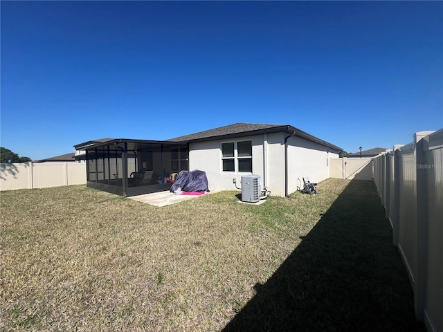 back of house with central AC, stucco siding, a lawn, a fenced backyard, and a sunroom