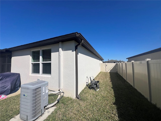 view of home's exterior featuring central air condition unit, stucco siding, a lawn, and a fenced backyard