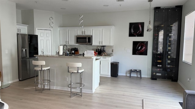10197 Ridgebloom Ave, Orlando, FL 32829 - kitchen with a kitchen bar, light wood-type flooring, white cabinetry, and stainless steel appliances