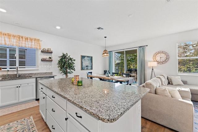1153 Augustus Dr, Davenport, FL 33896 - kitchen with stainless steel dishwasher, light wood-style floors, visible vents, and a sink