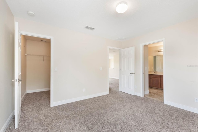 30439 Gidran Ter, Mount Dora, FL 32757 - unfurnished bedroom featuring baseboards, visible vents, a walk in closet, and light colored carpet