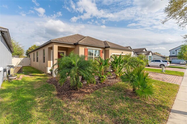 view of property exterior with stucco siding, a yard, and fence