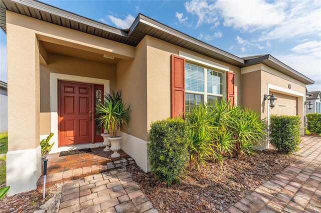 doorway to property with an attached garage and stucco siding
