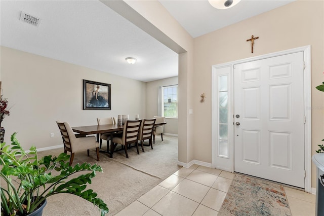 foyer entrance featuring light tile patterned floors, visible vents, baseboards, and light colored carpet