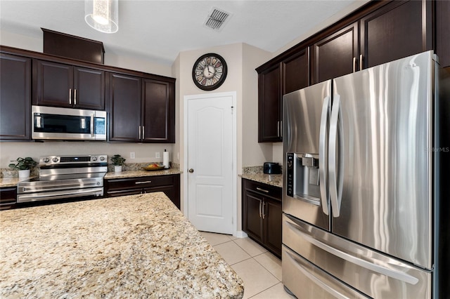 kitchen with visible vents, stainless steel appliances, light tile patterned floors, light stone countertops, and dark brown cabinets