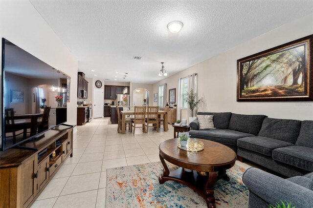 living area with visible vents, a textured ceiling, recessed lighting, arched walkways, and light tile patterned floors
