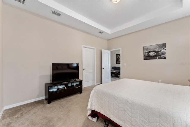 bedroom with carpet flooring, visible vents, a raised ceiling, and baseboards