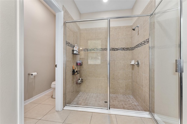 bathroom with tile patterned floors, a shower stall, toilet, and baseboards