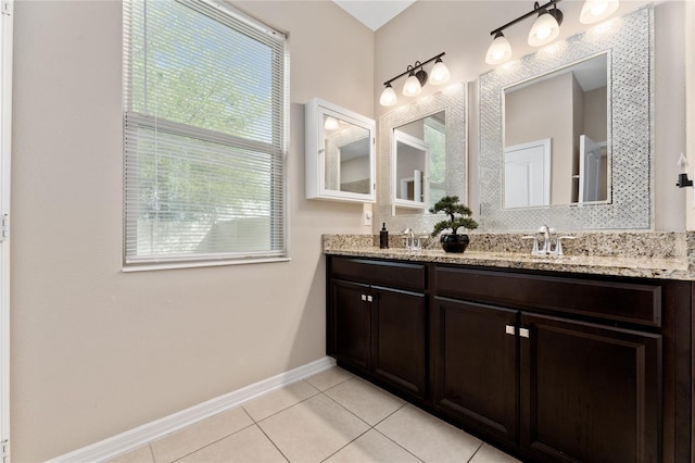 full bathroom featuring double vanity, baseboards, a sink, and tile patterned flooring