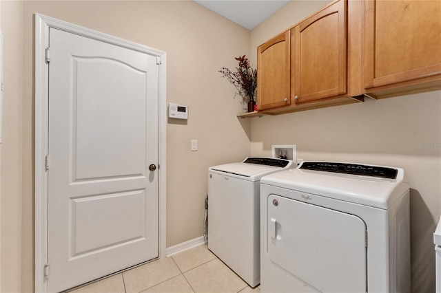 laundry room with light tile patterned floors, baseboards, cabinet space, and independent washer and dryer
