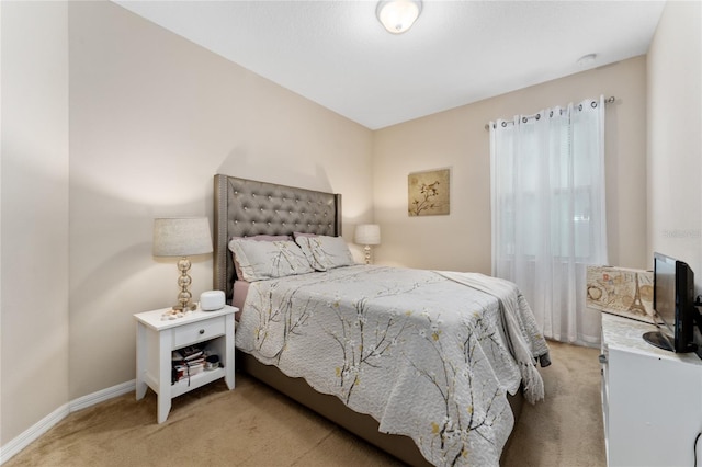 bedroom with light colored carpet and baseboards