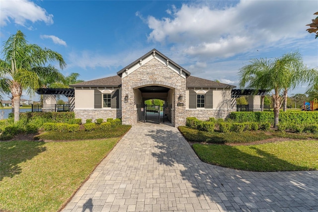 craftsman-style home featuring stucco siding, a gate, stone siding, fence, and a front yard