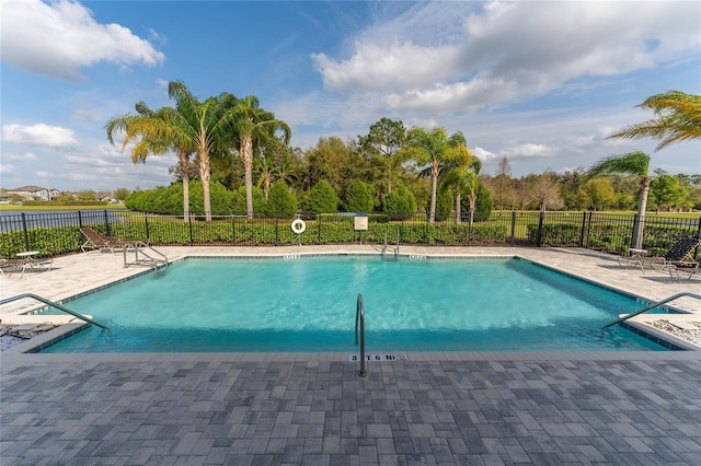 community pool with a patio area and fence