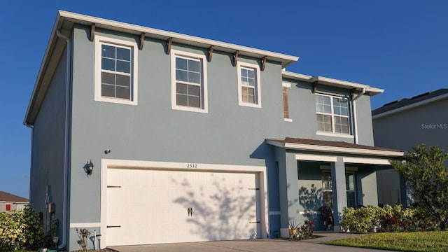 view of front facade with stucco siding, a garage, and concrete driveway