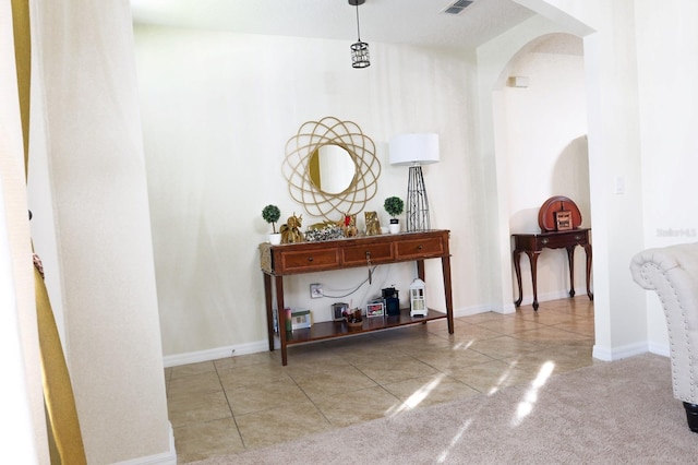 hall with tile patterned flooring, arched walkways, and baseboards