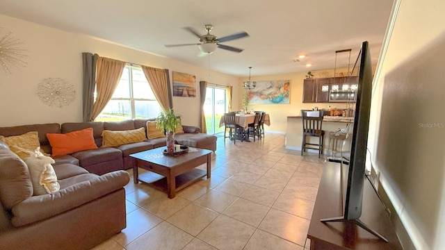 living area with light tile patterned floors, baseboards, and ceiling fan
