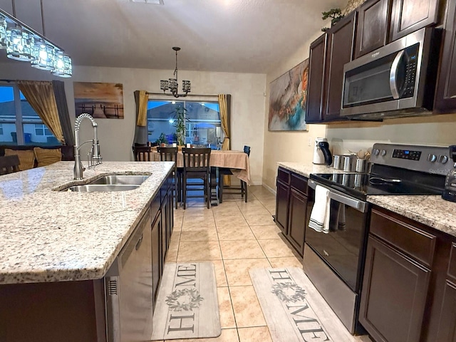 kitchen with a sink, light stone countertops, hanging light fixtures, stainless steel appliances, and dark brown cabinets
