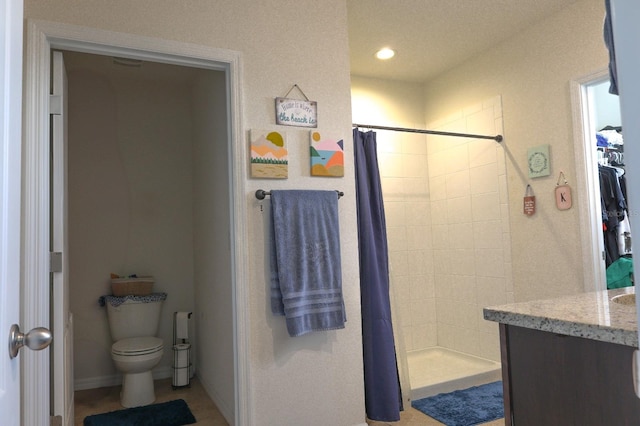 bathroom featuring toilet, vanity, tiled shower, and recessed lighting