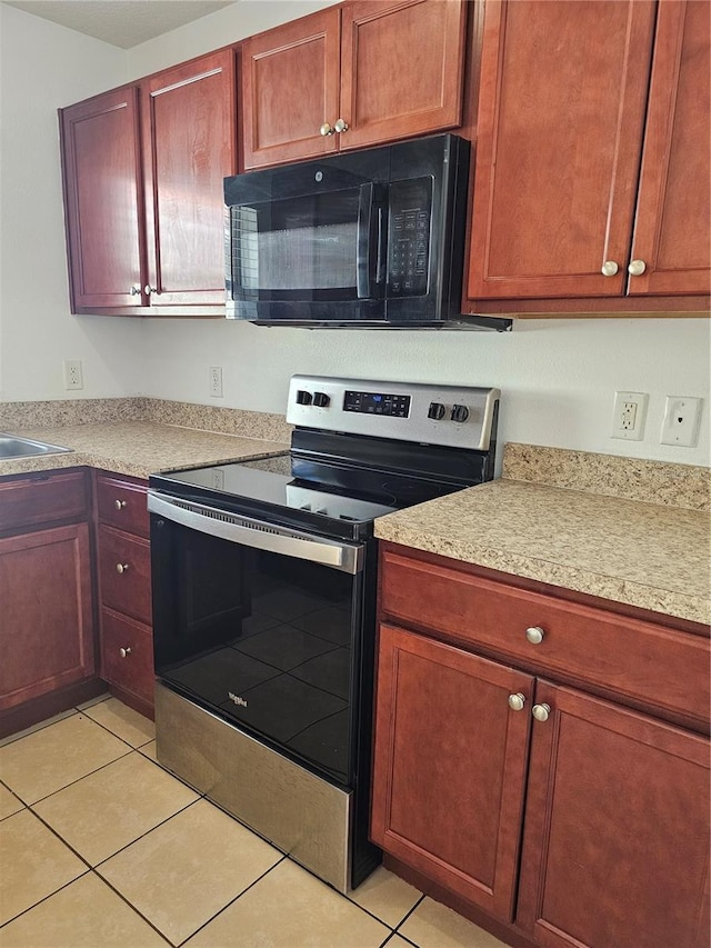 2921 Puerta Del Sol Blvd, Kissimmee, FL 34744 - kitchen featuring stainless steel electric range oven, light tile patterned flooring, light countertops, and black microwave