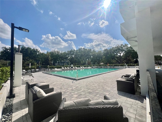 community pool with an outdoor living space and a patio area