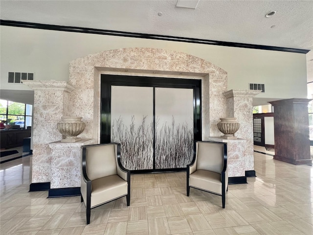 living area featuring visible vents, a textured ceiling, and crown molding