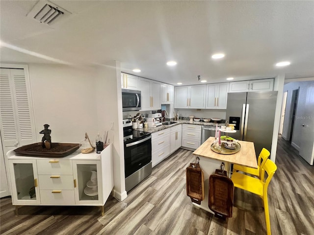 kitchen with visible vents, white cabinets, recessed lighting, wood finished floors, and stainless steel appliances
