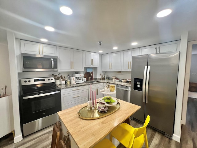kitchen featuring light wood-style floors, white cabinetry, recessed lighting, appliances with stainless steel finishes, and light stone counters