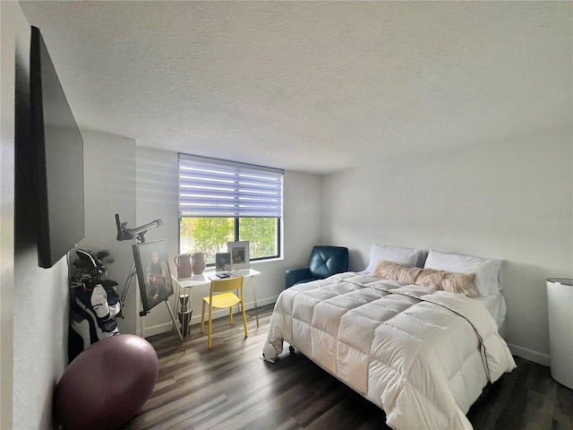bedroom with baseboards, a textured ceiling, and wood finished floors