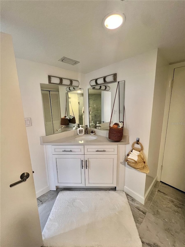 bathroom featuring visible vents, baseboards, and vanity