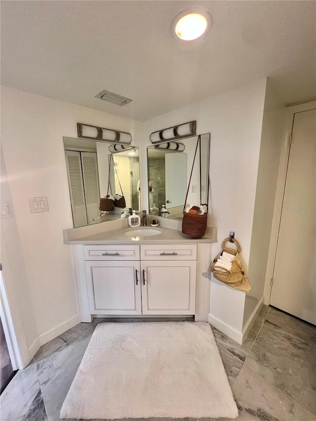 bathroom with vanity, visible vents, and baseboards