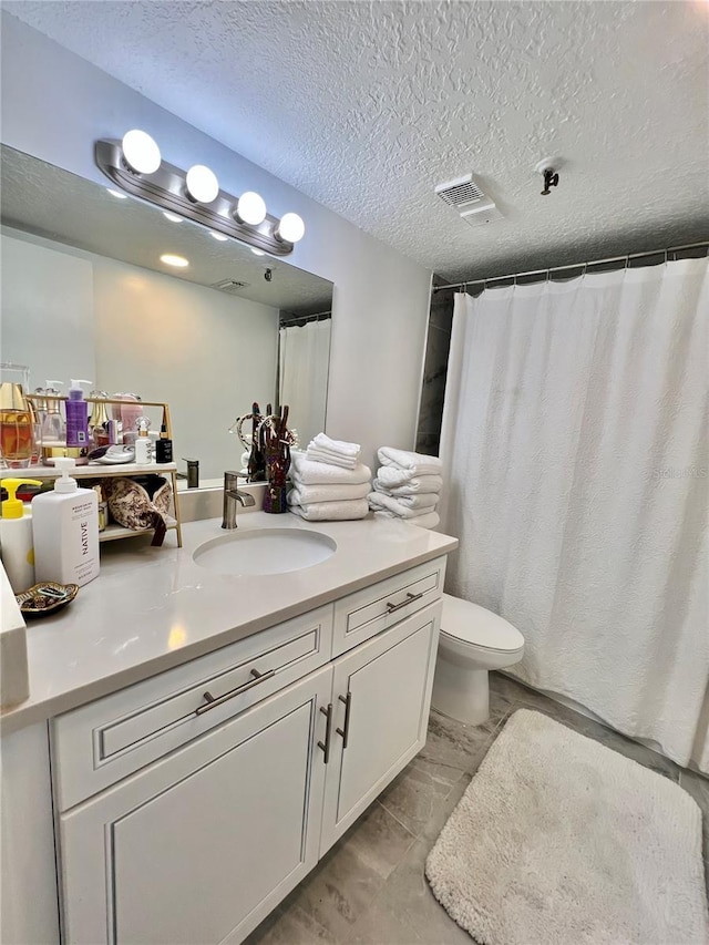 full bath featuring vanity, a textured ceiling, a shower with curtain, toilet, and visible vents