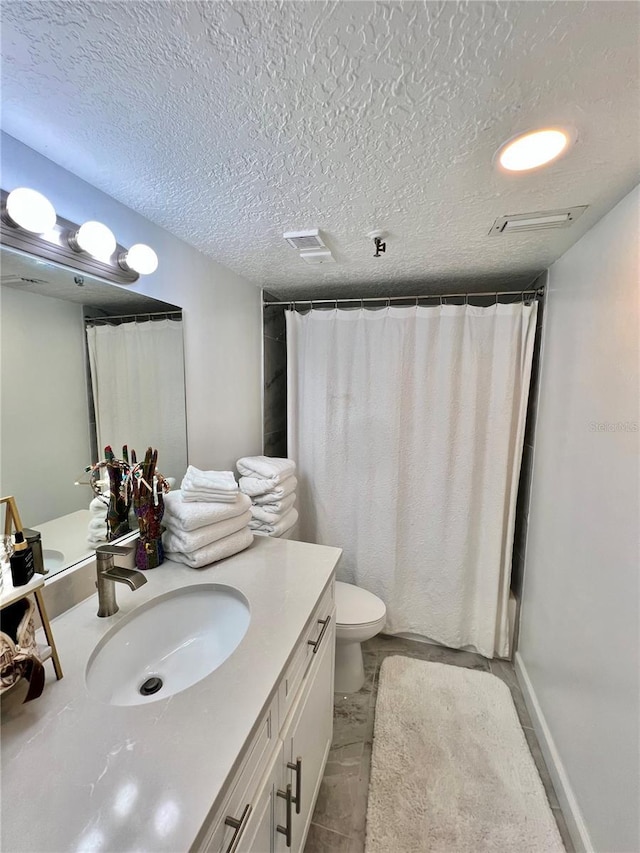 bathroom featuring visible vents, toilet, vanity, and a textured ceiling