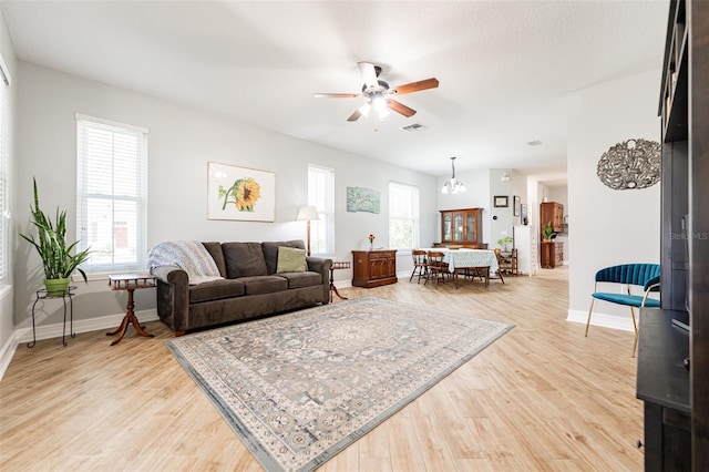 living area featuring visible vents, baseboards, light wood-style floors, and ceiling fan