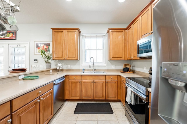 kitchen featuring light tile patterned flooring, light countertops, a sink, and stainless steel appliances