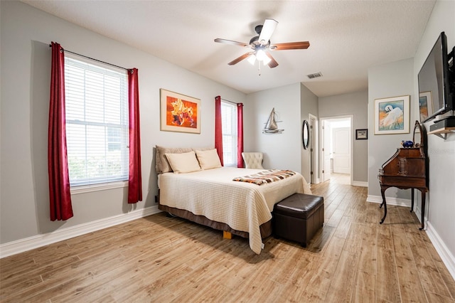 bedroom featuring baseboards, ceiling fan, visible vents, and light wood-style floors