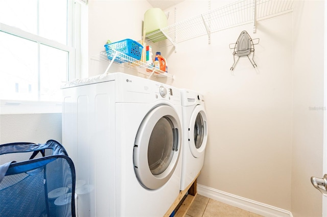 laundry room with light tile patterned flooring, washer and clothes dryer, baseboards, and laundry area