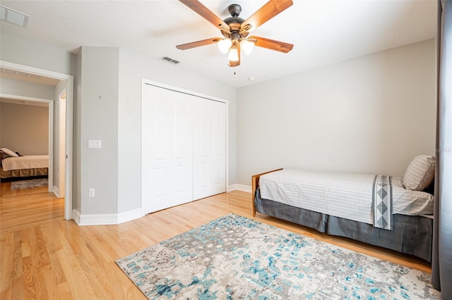 bedroom featuring a closet, baseboards, visible vents, and wood finished floors