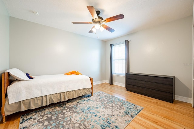 bedroom featuring light wood finished floors, baseboards, and a ceiling fan