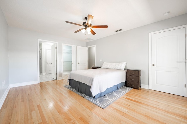 bedroom with baseboards, visible vents, a spacious closet, and light wood finished floors